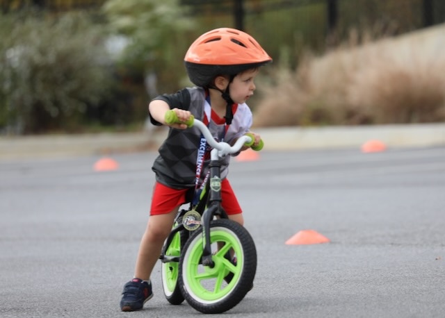 toddler balance bike class sitting and walking on a balance bike
